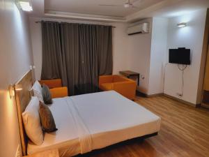 新德里Hotel Majestic stay - East of Kailash的一间卧室配有一张床、两把椅子和电视