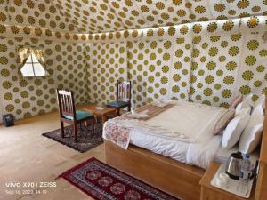 斋沙默尔Sam Safari Resort Jaisalmer的卧室配有1张床、1张桌子和1把椅子