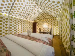 斋沙默尔Sam Safari Resort Jaisalmer的卧室配有一张床铺,位于带波卡圆点的房间