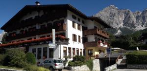圣维托-迪卡多雷Hotel Albergo Dolomiti的前面有停车位的建筑
