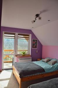 图霍拉Agroturystyka w Świcie的卧室设有紫色墙壁、床和窗户