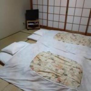 京都OHTO Ryokan的一张带白色床单的睡床