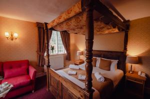 坎特伯雷豪菲尔德庄园酒店的一间卧室配有天蓬床和红色椅子