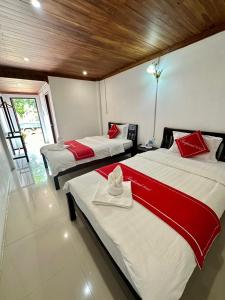 琅勃拉邦Residence Boutique Hotel的客房内的两张床,配有红色和白色床单