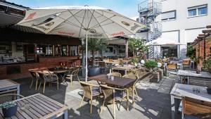 奥伯豪森豪斯友尼恩酒店的室外餐厅设有桌椅和遮阳伞。