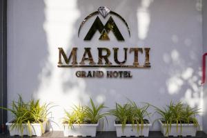 拉杰果德Maruti Grand Hotel的一座拥有盆栽植物的宏伟酒店标志