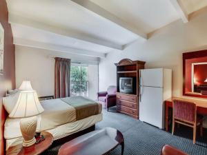 惠帕尼Red Carpet INN Whippany的配有床、书桌和冰箱的酒店客房