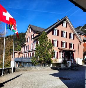 DallenwilPilgerhaus Maria-Rickenbach的粉色建筑物前的旗帜