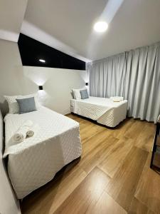 阿拉亚尔-杜卡布Suítes Viver Arraial do Cabo的铺有木地板的客房内的两张床