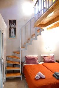 爱琴娜岛卡洛肯提公寓的一间卧室配有一张带橙色毯子和楼梯的床。