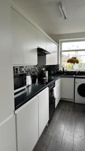 曼彻斯特Ur Place 204的厨房配有白色橱柜和黑色台面