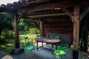 PolignacChambre d'Hôtes et gites du Tapissier的木制凉棚下的木桌和椅子