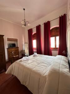 卡夏B&B PALAZZO SASSATELLI的卧室配有一张带红色窗帘的大型白色床