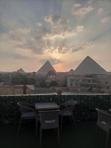 开罗Fantastic three pyramids view的一张桌子和椅子,后面是金字塔