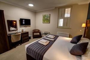 滨海绍森德罗奇福德酒店的一间卧室配有一张床、一张书桌和一台电视