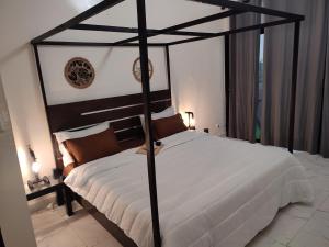 PoponguineLa residence latinaya的一间卧室配有黑色天蓬床和白色床单