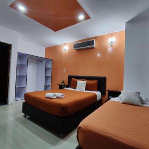 MéridaHOTEL MILLA SUITES MERIDA的一间卧室配有两张带橙色床单的床
