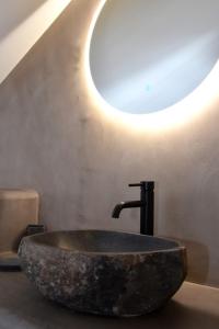 卡利斯托斯Αιγιαλίς - Πολυτελη διαμερισματα的浴室设有石水槽,墙上有灯