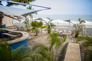 普拉亚科罗纳多Tower Suite Hotel Coronado的海滩上设有椅子和遮阳伞,还有大海