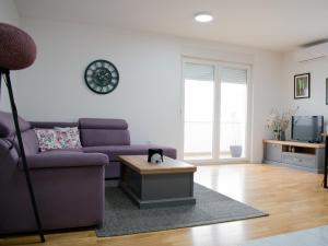 柳布什基An apartment M & K - 70 m2的客厅配有紫色沙发和桌子