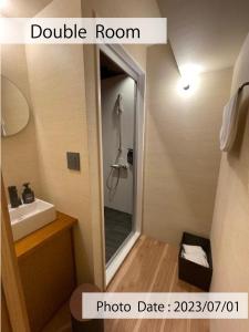 东京HOTEL TOMOS ASAKUSA的带淋浴、盥洗盆和镜子的浴室