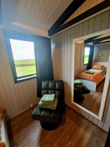 霍尔斯沃德吕尔Green Farm Stay with private hot tub的一间卧室配有镜子、椅子和一张床