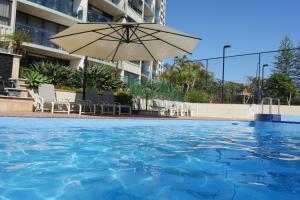 黄金海岸棕榈海滩公主酒店的一个带遮阳伞和椅子的游泳池
