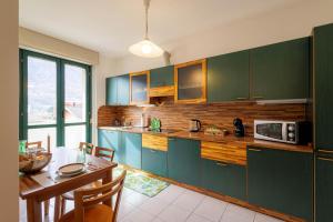 松德里奥Revo Apartments - Quadrifoglio的厨房配有绿色橱柜、餐桌和用餐室