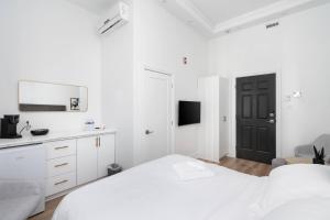 蒙特利尔Penfield Suites的白色的卧室设有白色的床和黑色的门