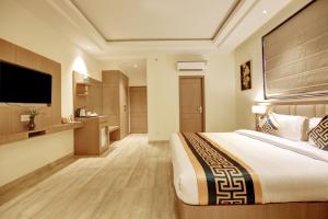 新德里Hotel AMBS suites A family Hotel Near Delhi Airport的配有一张床和一台平面电视的酒店客房