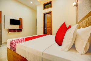 齐拉克普尔Super OYO Flagship Hotel Elista的一间卧室配有红色和白色枕头的床
