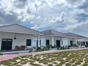Kampung MawarOcean Cottage 2, Radiant Teluk Sari的前面有草坪的白色房子