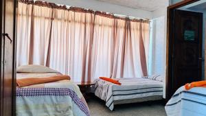 帕纳哈切尔Royal Palace Hostal的一间卧室设有两张床,窗户配有窗帘