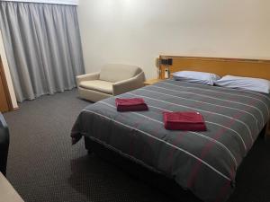 西怀厄朗True blue Motor Inn的配有一张床和一把椅子的酒店客房