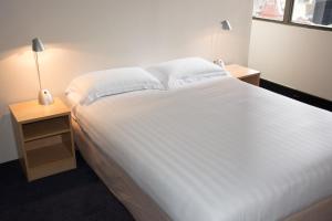 悉尼悉尼小憩酒店的一间卧室配有一张带2个床头柜的大型白色床