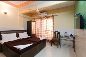 孟买Hotel classic residency的一间卧室配有一张床、一张桌子和一个窗户。