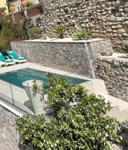 陶尔米纳陶尔米纳别墅酒店的一个带两把椅子和石墙的游泳池