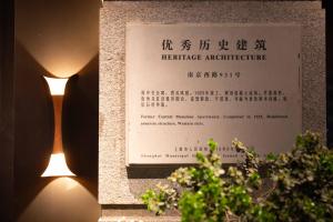 上海上海景莱不舍酒店的植物旁的遗产建筑标志