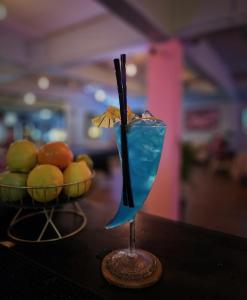 涛岛Tiki Tribe Bar & Hostel的坐在一碗水果旁边的桌子上喝的蓝色饮料