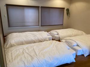 胜山市かつやま民泊きねん的配有白色床单的客房内的两张床