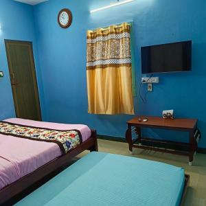 蓬蒂切里Blue Waves HomeStay的客房设有两张床、一台电视和一张桌子。