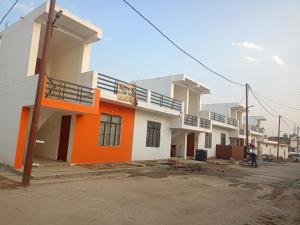 AyodhyaJankivihar Homestay at Prahladghat within 1km from Shri Ram Mandir的一座橙色和白色的房子,前面有一个人