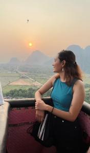 万荣万荣岩石背包客旅舍的坐在阳台上欣赏日落的女人