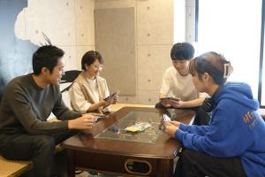 东京Hotel Tomariya Ueno的一群坐在桌子旁看手机的人