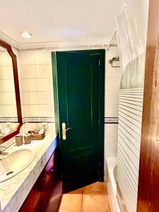 卡拉圣维森特Apartamento en Ibiza的绿色的门,浴室设有水槽和浴缸