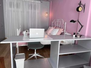塞萨洛尼基Retro House with Garden in Anopoli的粉红色客房内的白色书桌和笔记本电脑