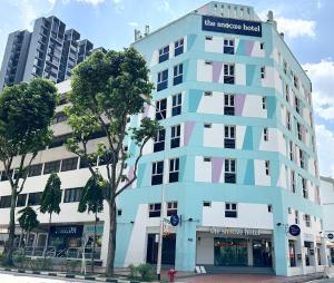 新加坡The Snooze Hotel at Bugis的城市街道上的一座蓝白色建筑