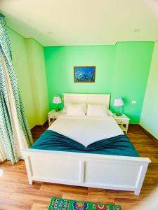 赫尔格达Tiba Rose hurghada的一间卧室配有白色的床和绿色的墙壁