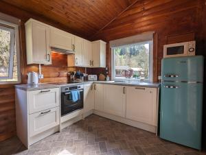 达农Ruskin Lodges Argyll, by Puck's Glen, Rashfield near Dunoon的厨房配有白色橱柜和蓝色冰箱。