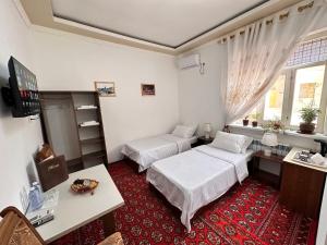 希瓦Gold Khiva的酒店客房设有两张床、一张书桌和一个窗户。